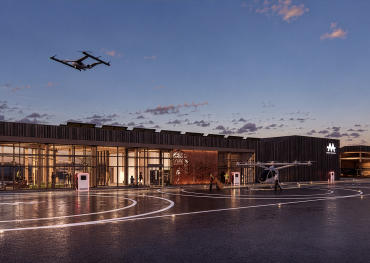 Concept rendering of a low-rise vertiport with a timber canopy, passenger entrance, roadway access and an electric aircraft visible beside the building.